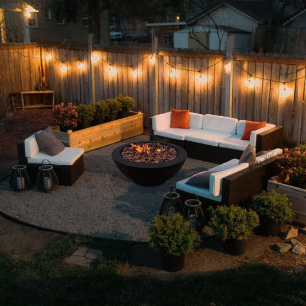 Stonelum Venecia 04 Concrete Fire Bowl black with fire on a backyard with evening lights 