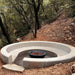 Stonelum Venecia 04 Concrete Fire Bowl black with lava rocks on a mountain backyard with trees