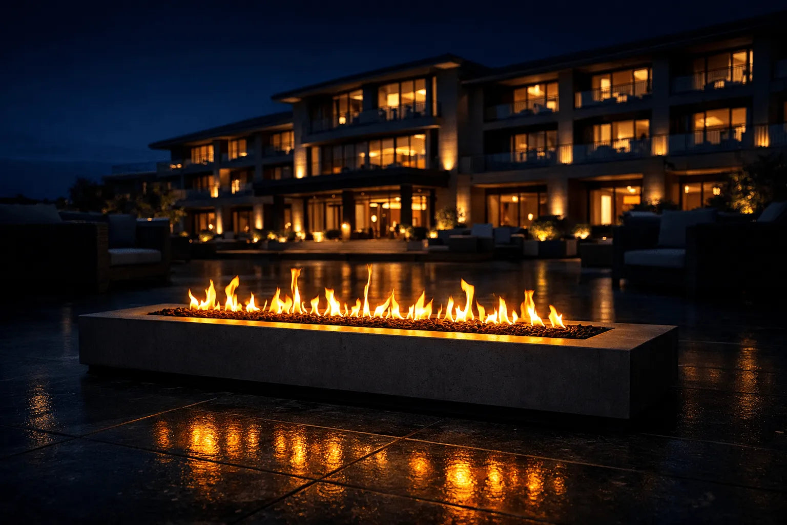 Fire pit with flames in front of a building at night

