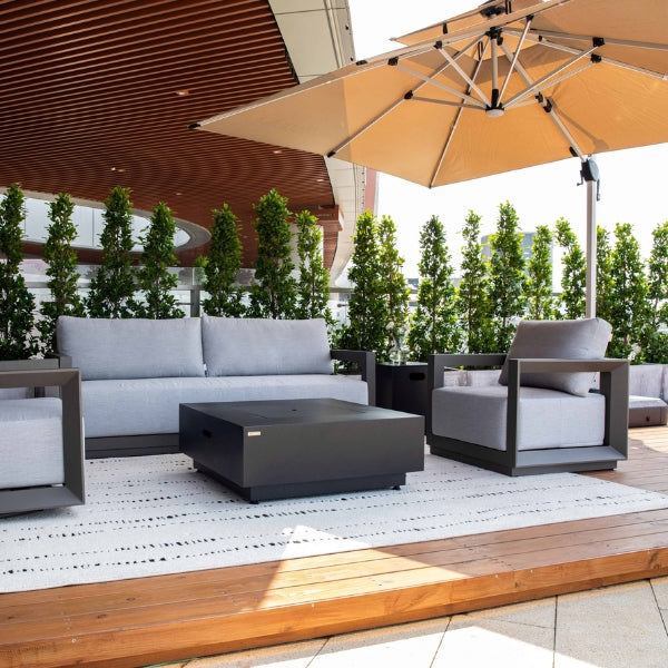 Outdoor patio furniture set with a fire pit table and umbrella on a wooden deck.