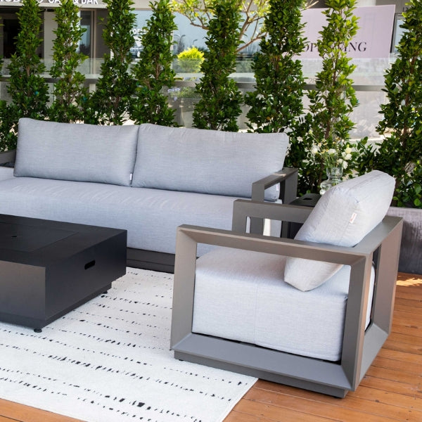 Outdoor patio furniture set with gray frame and white cushions on a wooden deck.