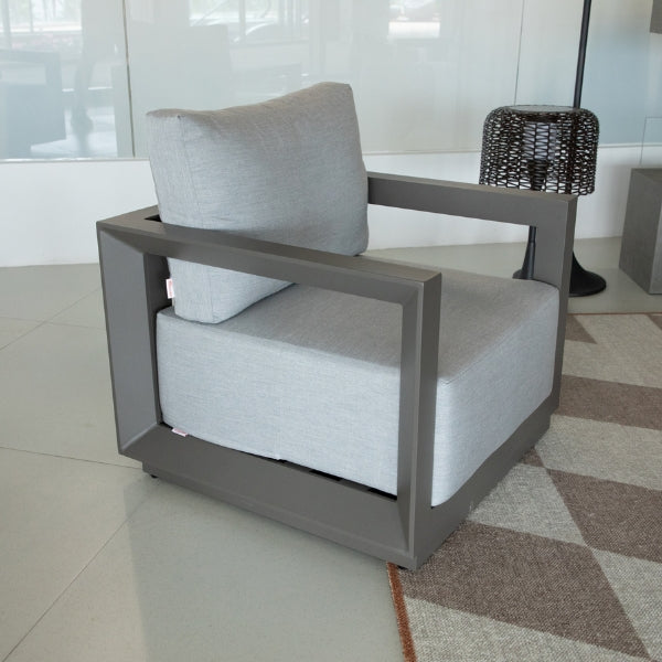 Modern armchair with gray cushion in a room with tiled floor and window.