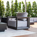 Modern outdoor furniture set with gray cushions on a wooden deck with green trees in the background