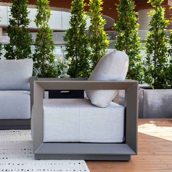 Modern outdoor chair with cushions on a wooden deck surrounded by greenery