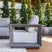 Modern outdoor chair with cushions on a wooden deck surrounded by greenery