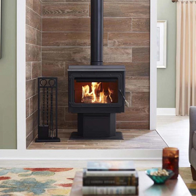 Englander 15-W06 Wood Stove with Blower takes center stage in front of a charming house design. Its sleek black design and glass door complement the house's aesthetics, offering both warmth and style