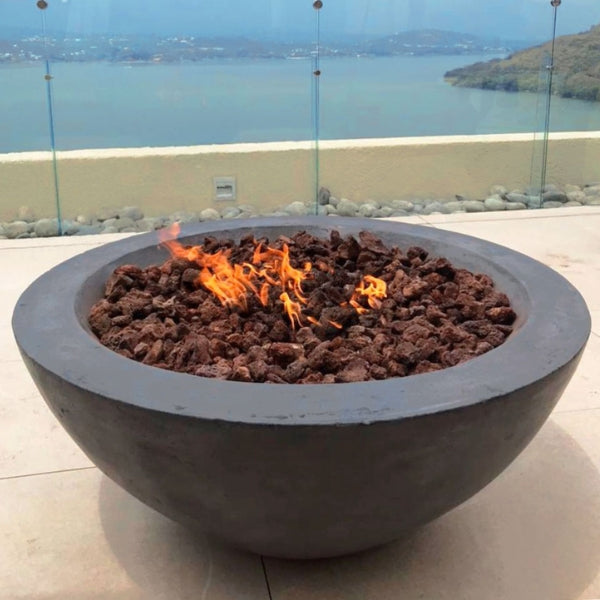Stonelum Venecia 04 Concrete Fire Bowl graphite with fire on a patio near the beach