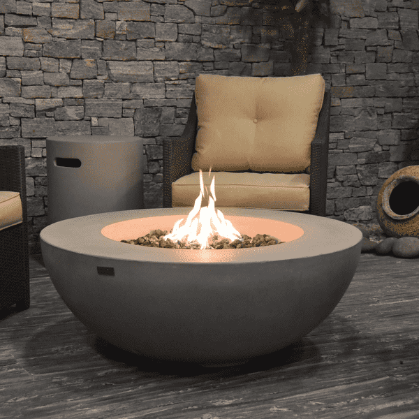 Elementi Lunar Round Concrete Fire Pit Table OFG101 Actual Photo with Flame, Accent Chair, and Round Tank Cover on a Covered Patio Set Up