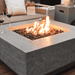 Elementi Manhattan Square Concrete Fire Pit Table OFG103 With Flame with Wine on Ledge and Square Tank Cover on Background