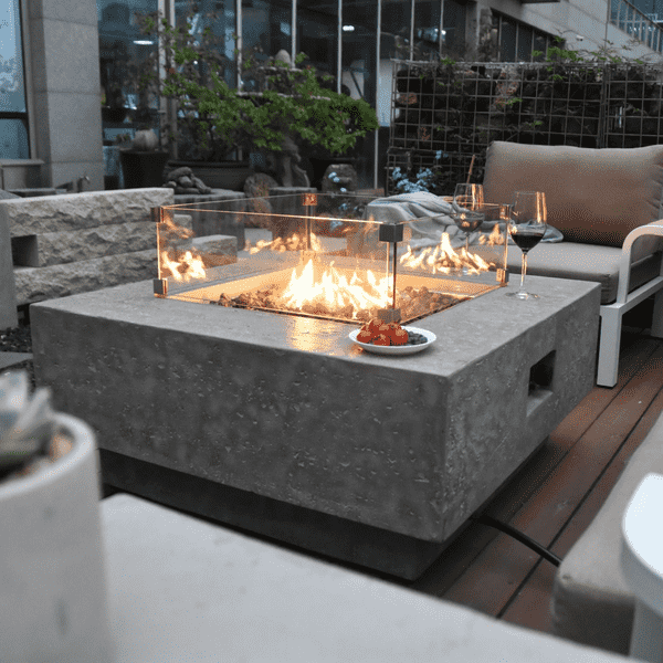 Elementi Manhattan Square Concrete Fire Pit Table OFG103 Actual Photo with Windscreen, Wine, Fruits on an a Deck Outdoor Set Up