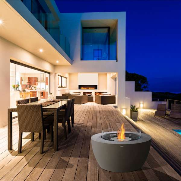 Ecosmart Fire Pod 40 Freestanding Fire Pit In Natural With Flame And Windscreen Placed On A Deck With Chairs And Table