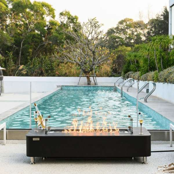 Elementi Plus Valencia Porcelain Top Fire Table OFP102BB With Flames In Pool Side Setting