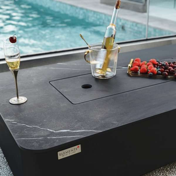 Elementi Plus Valencia Porcelain Top Fire Table OFP102BB With Food and Drinks on Top of the Cover