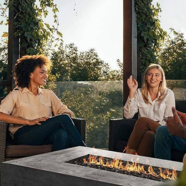    Prism Hardscapes Tavola 6 Concrete Gas Fire Table Ph 415 With Flame On The Center Of Two Women