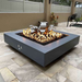 The Outdoor Plus Cabo Square Fire Pit In Gray With Flame On A Backyard Set Up