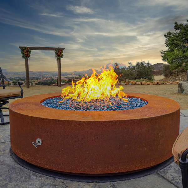 The Outdoor Plus Unity Metal Fire Pit In Corten Steel With Flame On An Outdoor Set Up